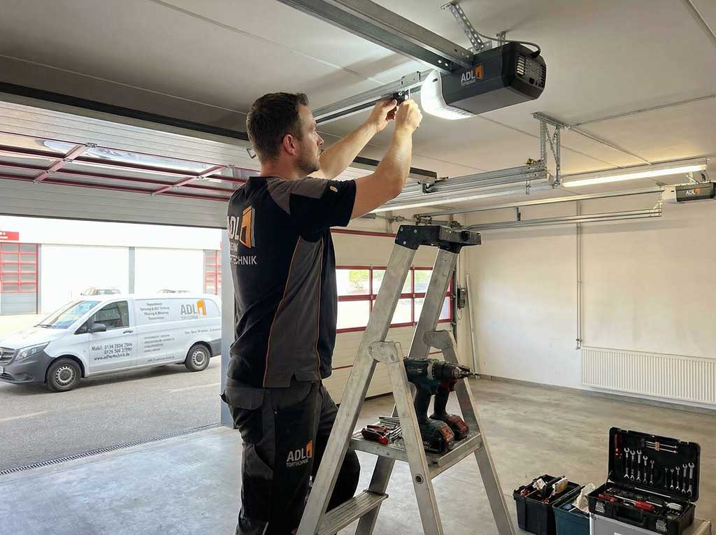 Fachgerechte Installation eines elektrischen Garagentorantriebs durch einen Techniker.